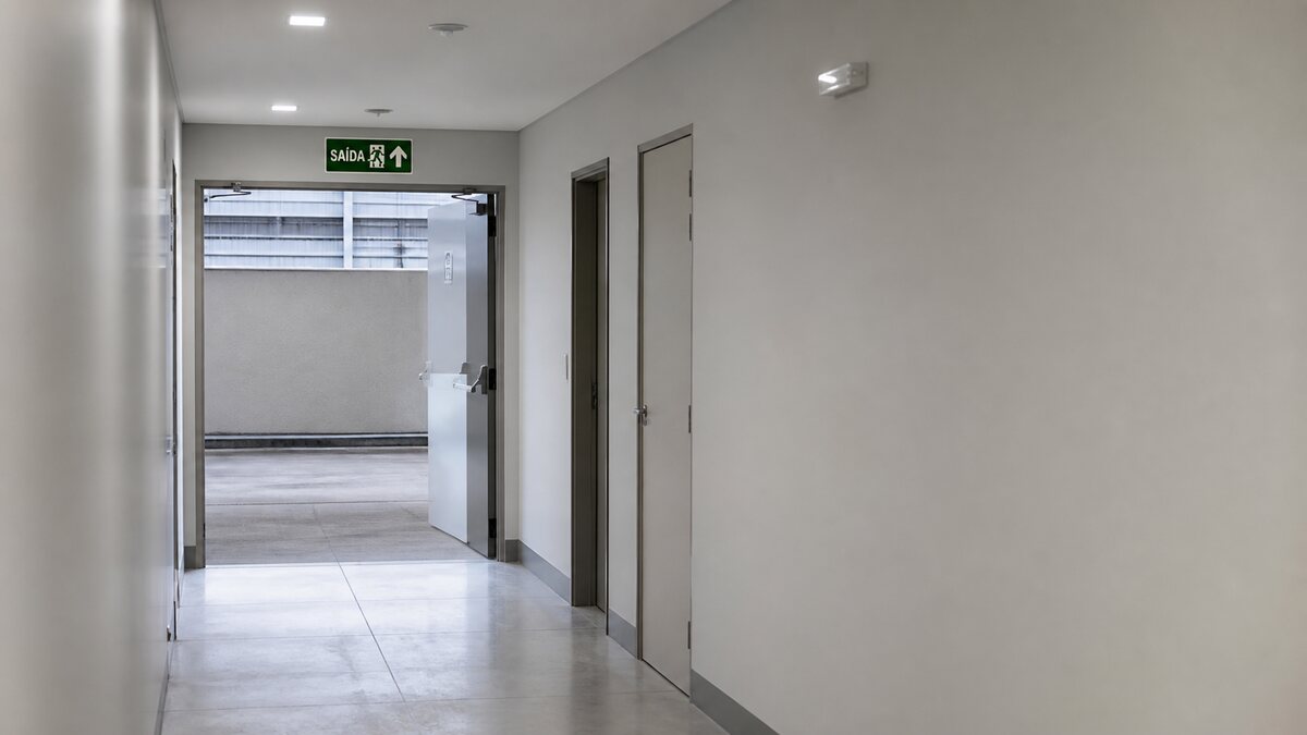 Corredor com sinalização e iluminação de emergência em rota de fuga